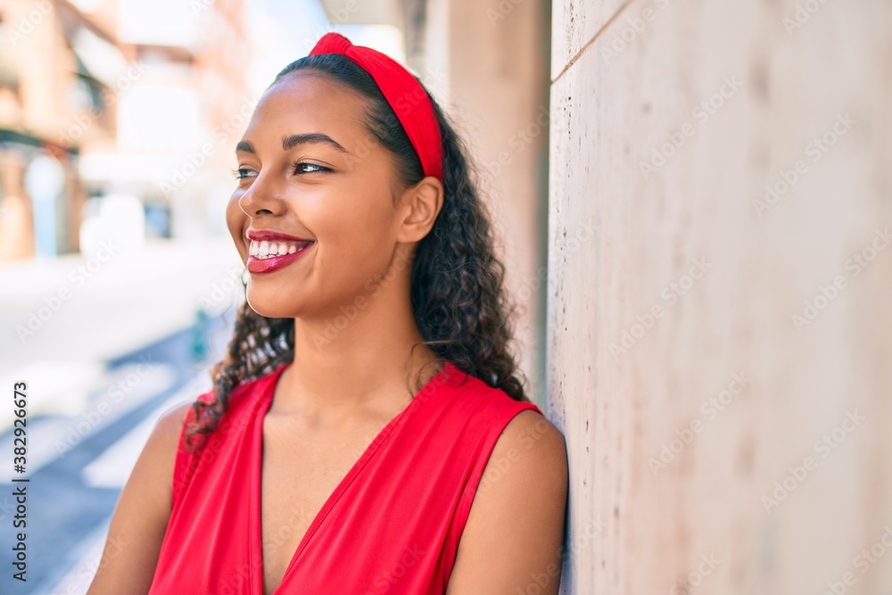 Young african american girl smiling happy leaning on the wall at city. Young african american girl smiling happy leaning on the wall at city.