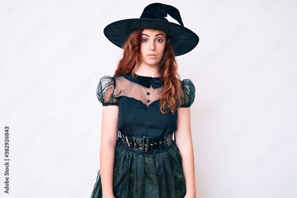 Young beautiful woman wearing witch halloween costume relaxed with serious expression on face. simple and natural looking at the camera. Young beautiful woman wearing witch halloween costume relaxed with serious expression on face. simple and natural looking at the camera.