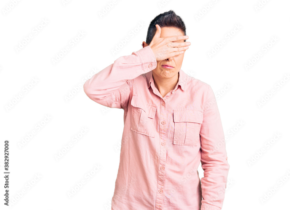 Young woman with short hair wearing casual clothes covering eyes with hand, looking serious and sad. sightless, hiding and rejection concept Young woman with short hair wearing casual clothes covering eyes with hand, looking serious and sad. sightless, hiding and rejection concept