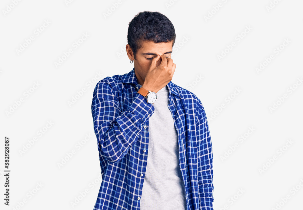 Young african amercian man wearing casual clothes tired rubbing nose and eyes feeling fatigue and headache. stress and frustration concept. Young african amercian man wearing casual clothes tired rubbing nose and eyes feeling fatigue and headache. stress and frustration concept.