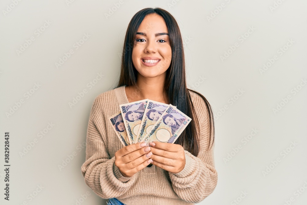 Young beautiful hispanic girl holding japanese yen banknotes smiling with a happy and cool smile on face. showing teeth. Young beautiful hispanic girl holding japanese yen banknotes smiling with a happy and cool smile on face. showing teeth.