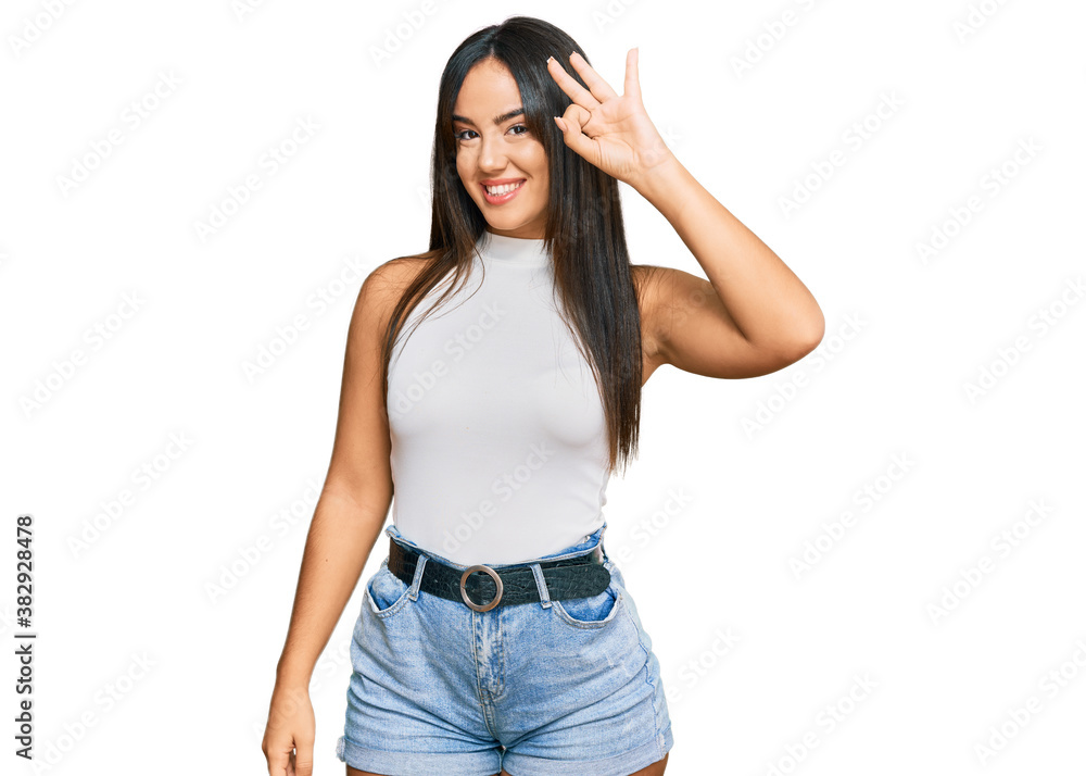 Young beautiful hispanic girl wearing casual clothes smiling positive doing ok sign with hand and fingers. successful expression. Young beautiful hispanic girl wearing casual clothes smiling positive doing ok sign with hand and fingers. successful expression.