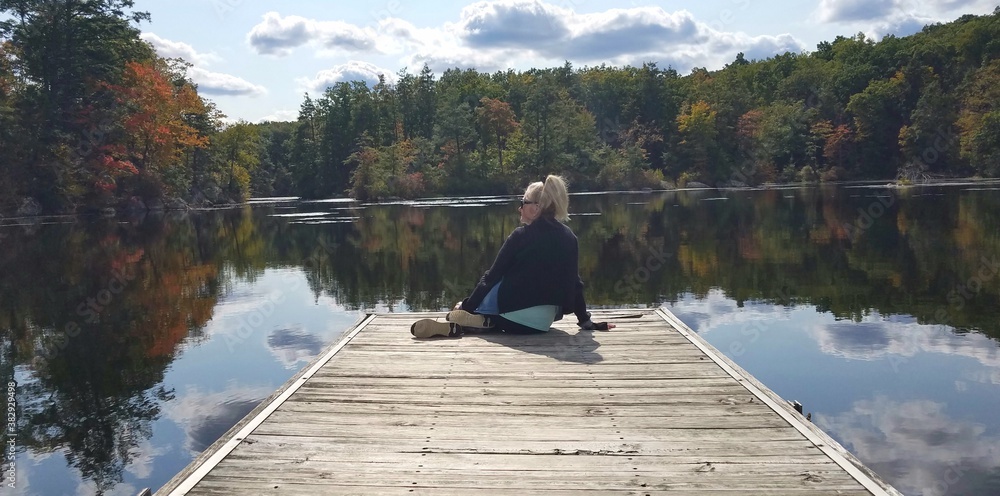 Person Sitting on the Edge of a Dock With a Stunning Nature Background Person Sitting on the Edge of a Dock With a Stunning Nature Background