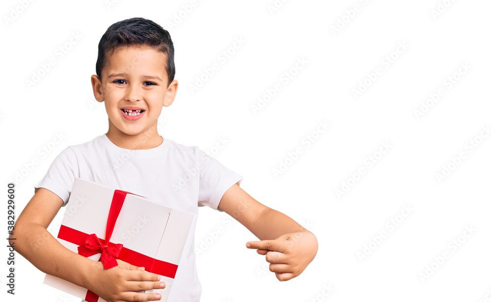 Little cute boy kid holding gift smiling happy pointing with hand and finger Little cute boy kid holding gift smiling happy pointing with hand and finger