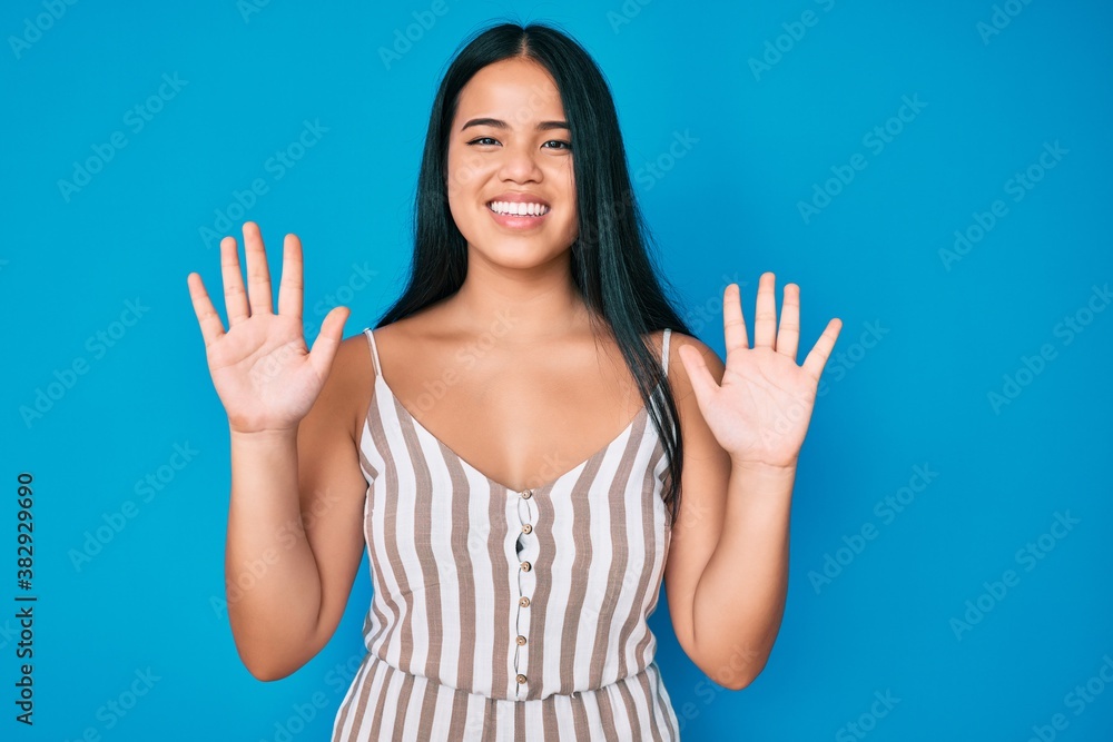 Young beautiful asian girl wearing casual clothes showing and pointing up with fingers number ten while smiling confident and happy. Young beautiful asian girl wearing casual clothes showing and pointing up with fingers number ten while smiling confident and happy.