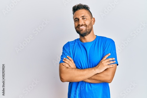 Handsome man with beard wearing casual clothes happy face smiling with crossed arms looking at the camera. positive person.