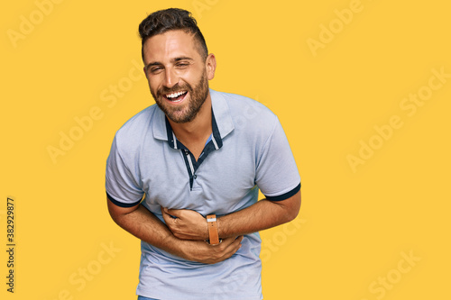 Handsome man with beard wearing casual clothes smiling and laughing hard out loud because funny crazy joke with hands on body.