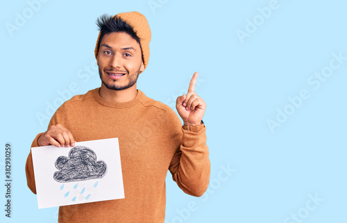 Obraz na plátně Handsome latin american young man holding rain draw surprised with an idea or qu