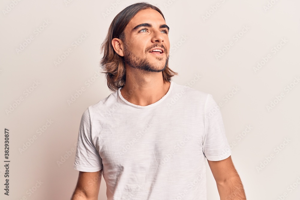Young handsome man wearing casual clothes looking away to side with smile on face, natural expression. laughing confident. Young handsome man wearing casual clothes looking away to side with smile on face, natural expression. laughing confident.