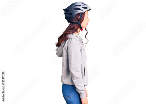 Young beautiful chinese girl wearing bike helmet looking to side, relax profile pose with natural face with confident smile.
