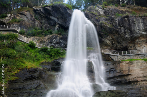 Fototapeta Naklejka Na Ścianę i Meble -  Long Time Exposure Of Steindalsfossen Falls In The Fosselva River In Norway On A Sunny Summer Day With A Clear Blue Sky And A Few Clouds