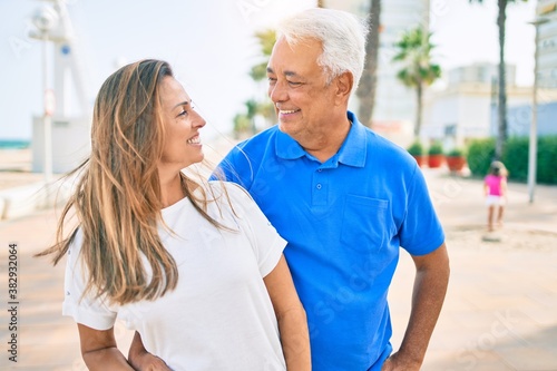 Middle age hispanic couple smiling happy hugging at the promenade.