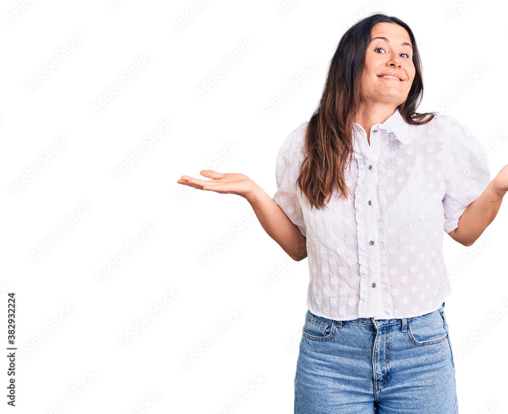 Young beautiful brunette woman wearing casual shirt clueless and confused expression with arms and hands raised. doubt concept. Young beautiful brunette woman wearing casual shirt clueless and confused expression with arms and hands raised. doubt concept.