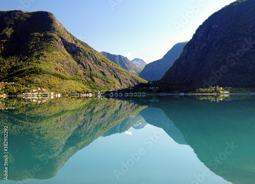 Mountains Reflecting In The Calm Water Of The Dalsfjord Near Skjolden On A Sunny Summer Day With A Clear Blue Sky And A Few Clouds