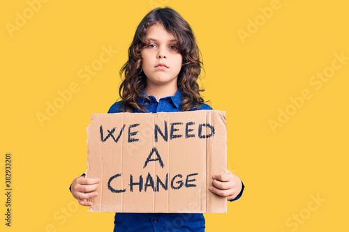Fotografie Cute hispanic child with long hair holding we need a change banner thinking atti