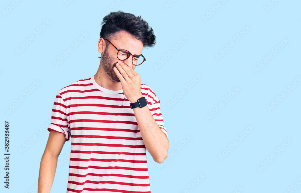 Young hispanic man wearing casual clothes smelling something stinky and disgusting, intolerable smell, holding breath with fingers on nose. bad smell Young hispanic man wearing casual clothes smelling something stinky and disgusting, intolerable smell, holding breath with fingers on nose. bad smell