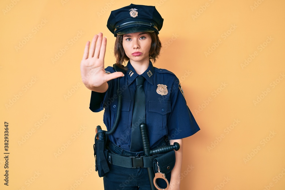 Young beautiful woman wearing police uniform doing stop sing with palm of the hand. warning expression with negative and serious gesture on the face. Young beautiful woman wearing police uniform doing stop sing with palm of the hand. warning expression with negative and serious gesture on the face.