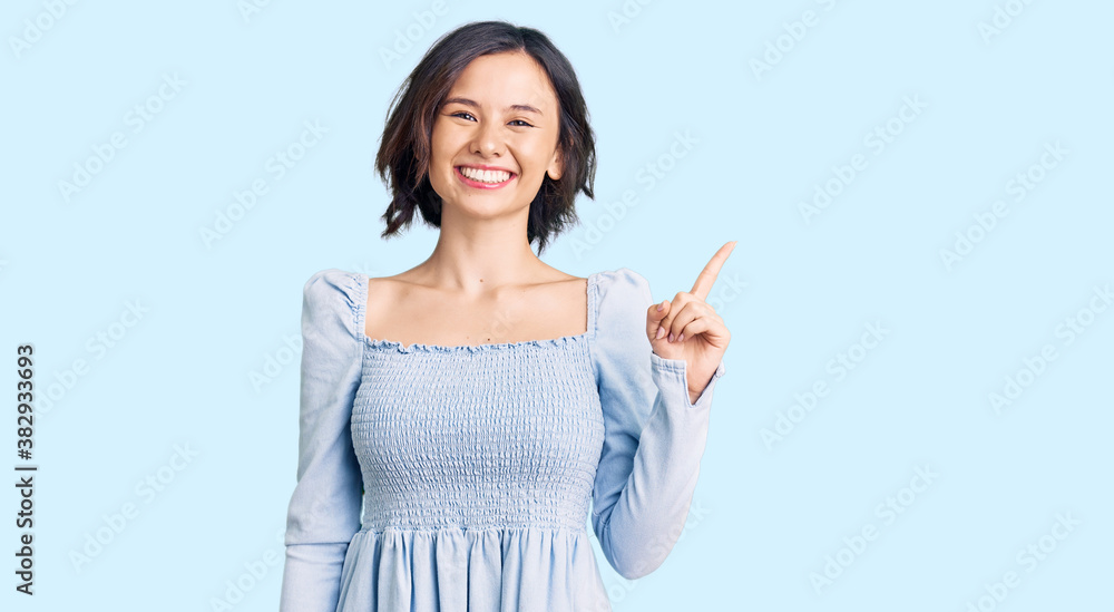 Young beautiful girl wearing casual clothes with a big smile on face, pointing with hand finger to the side looking at the camera. Young beautiful girl wearing casual clothes with a big smile on face, pointing with hand finger to the side looking at the camera.