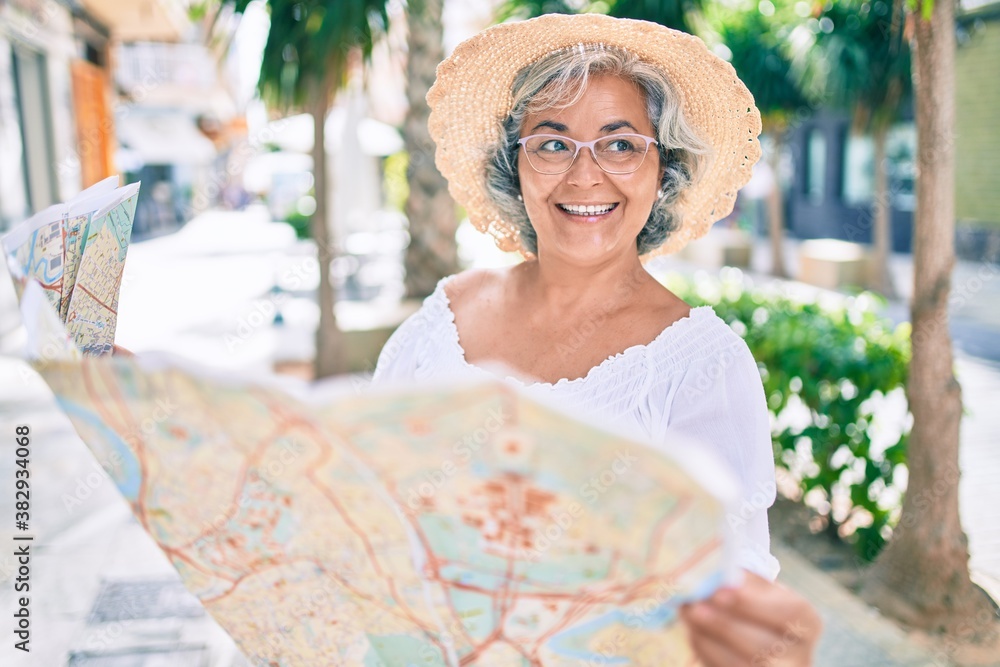Middle age tourist woman with grey hair looking at city map on a summer trip on holidays