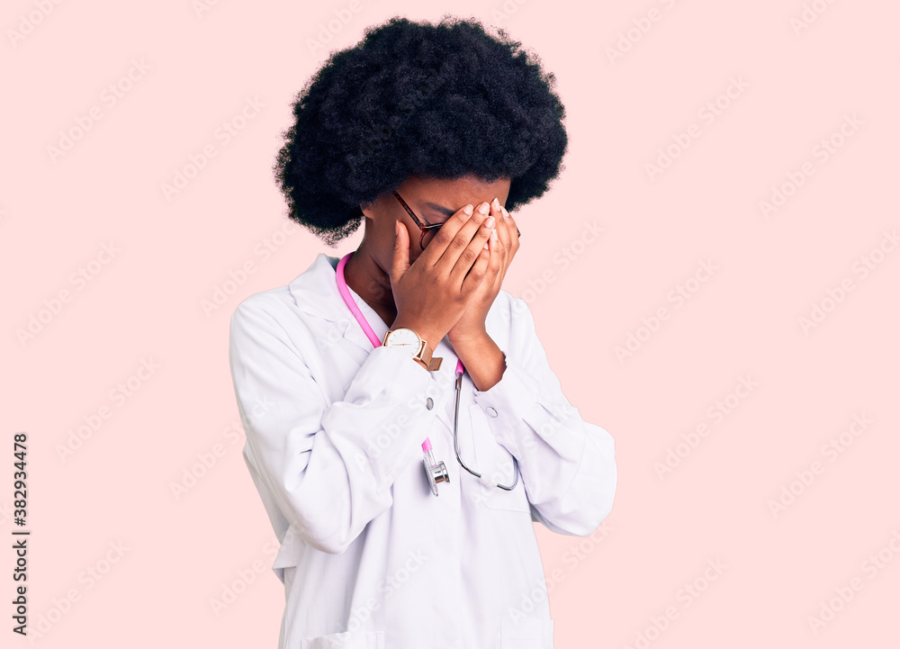 Young african american woman wearing doctor coat and stethoscope with sad expression covering face with hands while crying. depression concept. Young african american woman wearing doctor coat and stethoscope with sad expression covering face with hands while crying. depression concept.