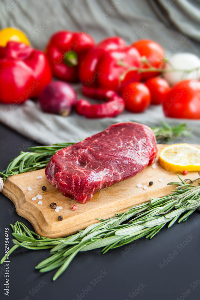 Raw beef steak on a cutting board with spices. Creative atmospheric decoration