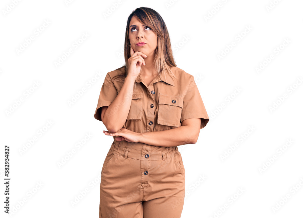 Young beautiful woman wearing casual dress serious face thinking about question with hand on chin, thoughtful about confusing idea Young beautiful woman wearing casual dress serious face thinking about question with hand on chin, thoughtful about confusing idea