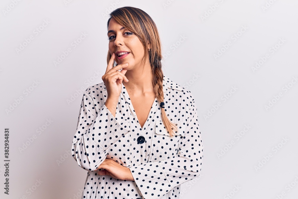 Young beautiful woman wearing casual dress smiling looking confident at the camera with crossed arms and hand on chin. thinking positive. Young beautiful woman wearing casual dress smiling looking confident at the camera with crossed arms and hand on chin. thinking positive.