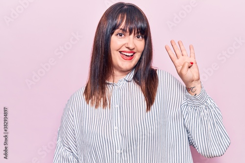 Young plus size woman wearing casual clothes showing and pointing up with fingers number four while smiling confident and happy.