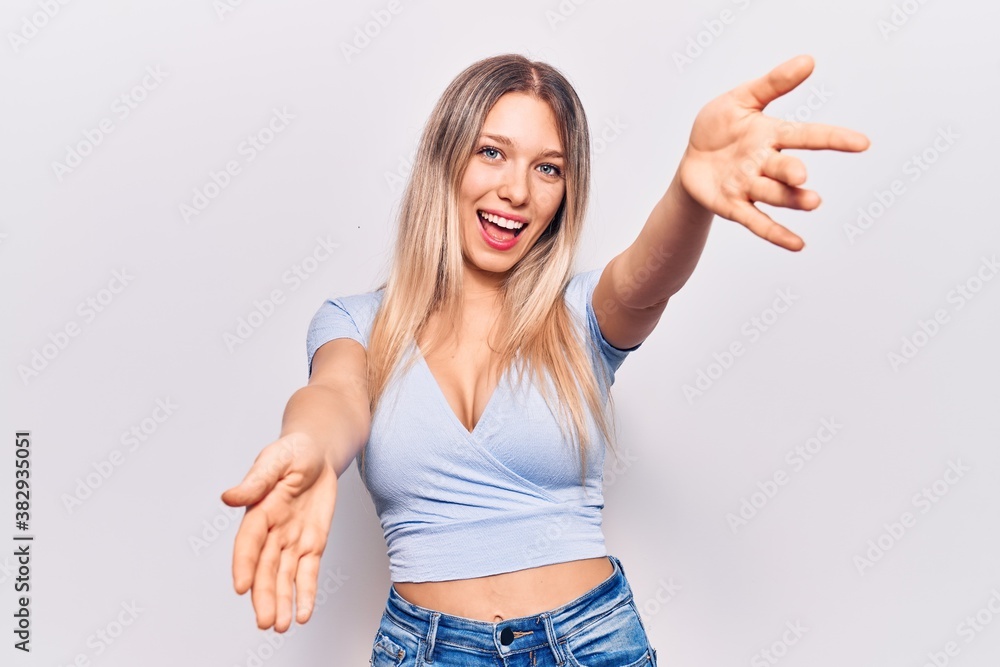 Young blonde woman wearing casual clothes looking at the camera smiling with open arms for hug. cheerful expression embracing happiness. Young blonde woman wearing casual clothes looking at the camera smiling with open arms for hug. cheerful expression embracing happiness.