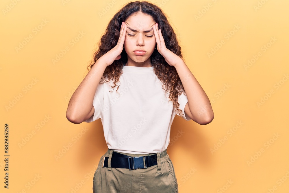 Beautiful kid girl with curly hair wearing casual clothes suffering from headache desperate and stressed because pain and migraine. hands on head. Beautiful kid girl with curly hair wearing casual clothes suffering from headache desperate and stressed because pain and migraine. hands on head.