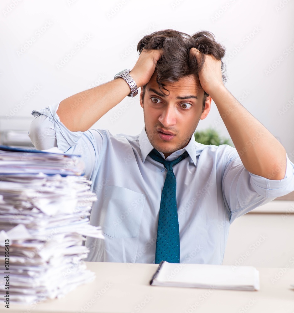 Overloaded busy employee with too much work and paperwork Overloaded busy employee with too much work and paperwork