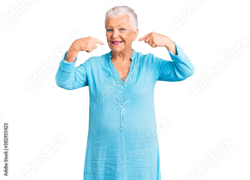 Senior beautiful woman with blue eyes and grey hair wearing summer dress smiling cheerful showing and pointing with fingers teeth and mouth. dental health concept.
