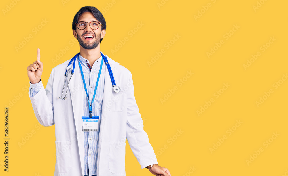 Handsome hispanic man wearing doctor uniform and stethoscope pointing finger up with successful idea. exited and happy. number one. Handsome hispanic man wearing doctor uniform and stethoscope pointing finger up with successful idea. exited and happy. number one.