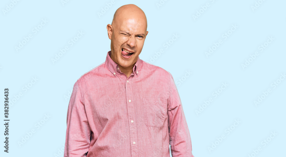 Middle age bald man wearing casual clothes winking looking at the camera with sexy expression, cheerful and happy face. Middle age bald man wearing casual clothes winking looking at the camera with sexy expression, cheerful and happy face.