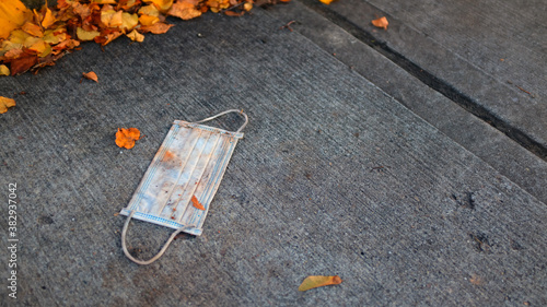 Blue Disposable Face Mask Discarded on Sideway by Autumn Leaves