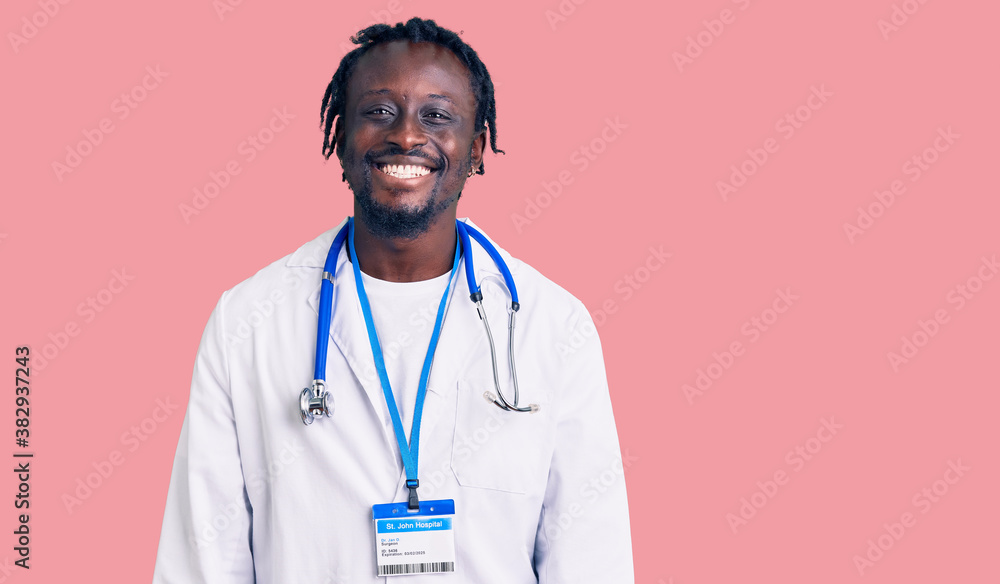 Young african american man with braids wearing doctor stethoscope and id pass looking positive and happy standing and smiling with a confident smile showing teeth Young african american man with braids wearing doctor stethoscope and id pass looking positive and happy standing and smiling with a confident smile showing teeth