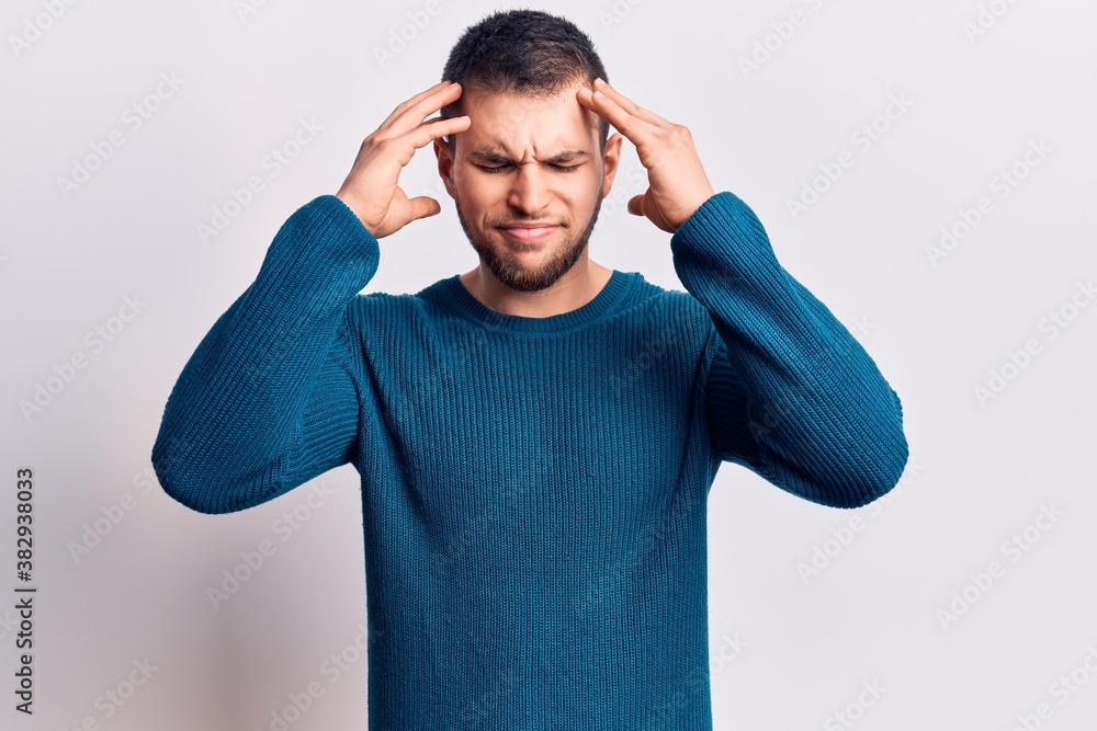 Young handsome man wearing casual sweater with hand on head, headache because stress. suffering migraine. Young handsome man wearing casual sweater with hand on head, headache because stress. suffering migraine.