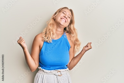 Young blonde girl wearing casual clothes very happy and excited doing winner gesture with arms raised, smiling and screaming for success. celebration concept. © Krakenimages.com