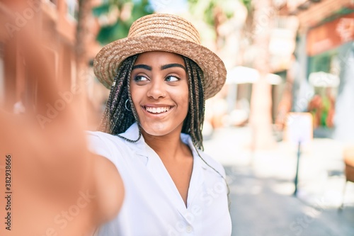 Young african american woman with braids smiling happy taking selfie picture outdoors on a sunny day of summer © Krakenimages.com