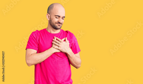 Young handsome man wearing casual t shirt smiling with hands on chest with closed eyes and grateful gesture on face. health concept.