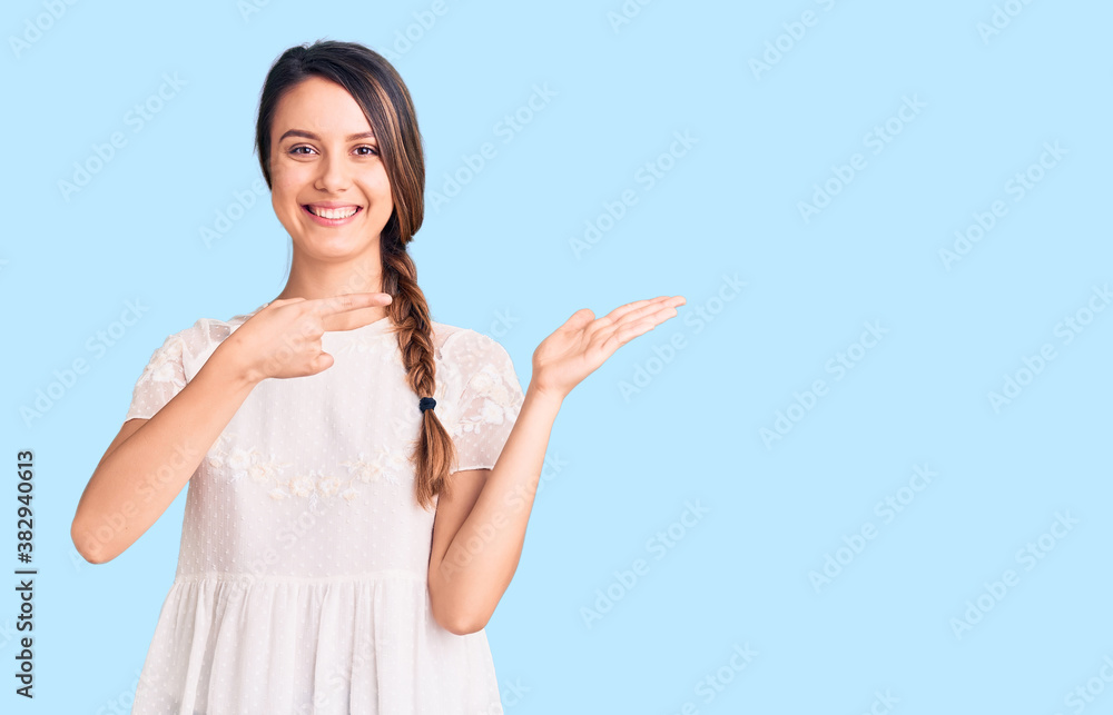 Young beautiful girl wearing casual t shirt amazed and smiling to the camera while presenting with hand and pointing with finger. Young beautiful girl wearing casual t shirt amazed and smiling to the camera while presenting with hand and pointing with finger.