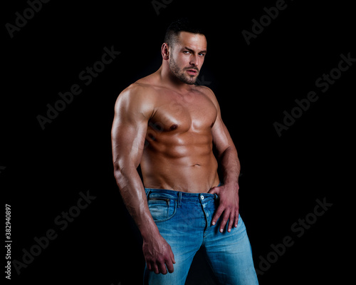 Sexy man with muscular body and bare torso on black.