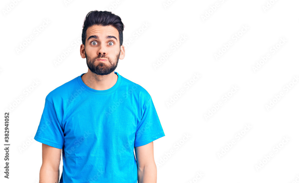 Young handsome man with beard wearing casual t-shirt puffing cheeks with funny face. mouth inflated with air, crazy expression. Young handsome man with beard wearing casual t-shirt puffing cheeks with funny face. mouth inflated with air, crazy expression.
