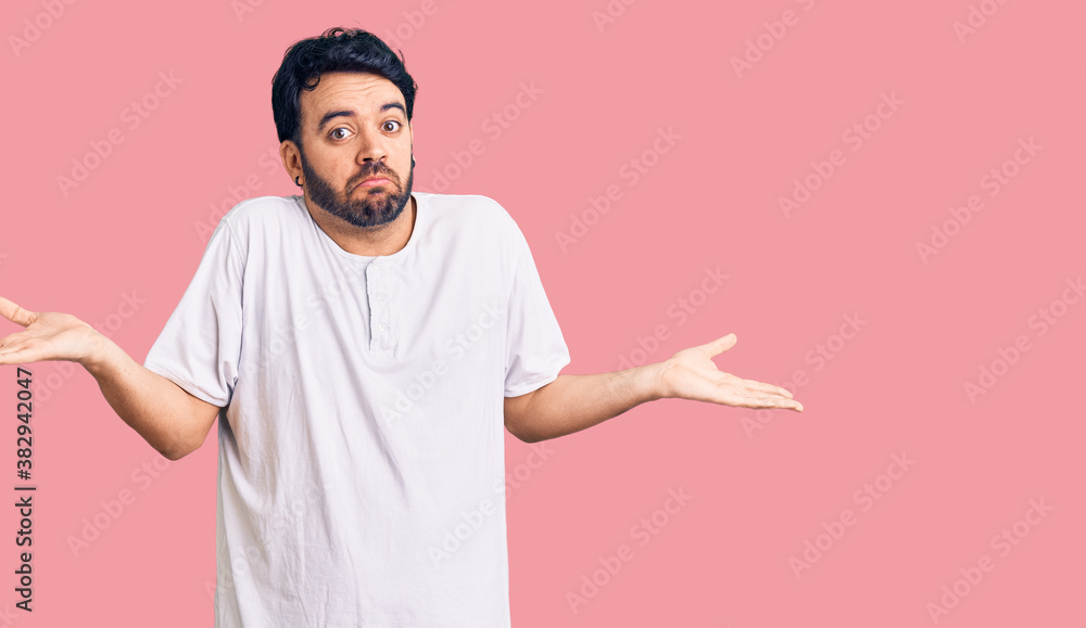 Young hispanic man wearing casual clothes clueless and confused expression with arms and hands raised. doubt concept. Young hispanic man wearing casual clothes clueless and confused expression with arms and hands raised. doubt concept.