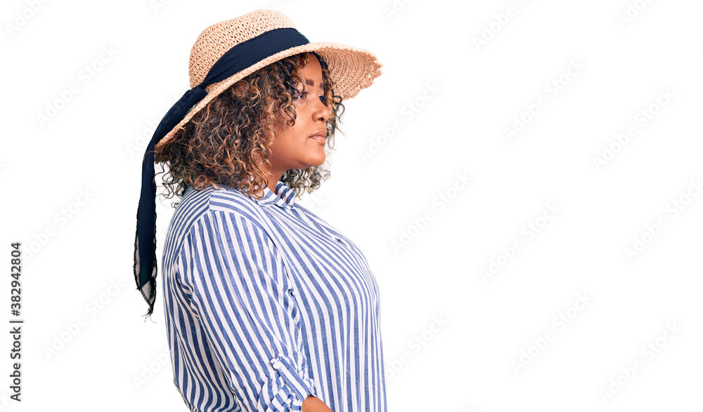 Young african american plus size woman wearing summer hat looking to side, relax profile pose with natural face with confident smile. Young african american plus size woman wearing summer hat looking to side, relax profile pose with natural face with confident smile.