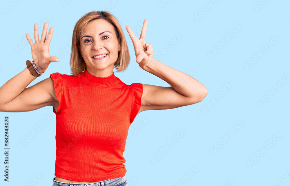Fototapeta premium Young blonde woman wearing casual clothes showing and pointing up with fingers number eight while smiling confident and happy.