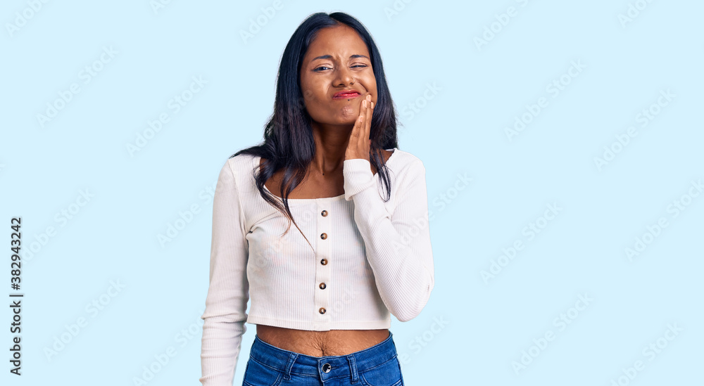 Young indian girl wearing casual clothes touching mouth with hand with painful expression because of toothache or dental illness on teeth. dentist Young indian girl wearing casual clothes touching mouth with hand with painful expression because of toothache or dental illness on teeth. dentist