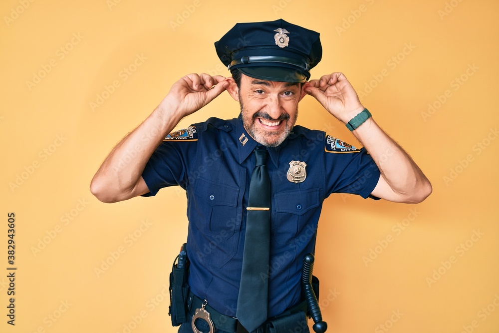 Middle age hispanic man wearing police uniform smiling pulling ears with fingers, funny gesture. audition problem Middle age hispanic man wearing police uniform smiling pulling ears with fingers, funny gesture. audition problem