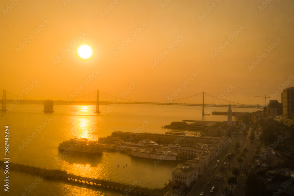 Fototapeta premium Eerie orange sky over Bay Bridge in San Francisco, drone image