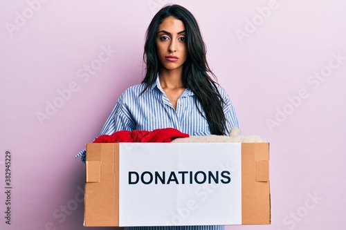 Beautiful hispanic woman volunteer holding donations box skeptic and nervous, frowning upset because of problem. negative person. © Krakenimages.com